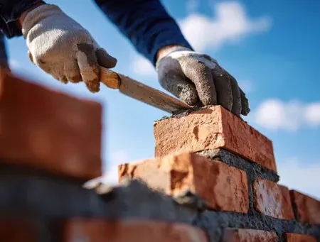 Mason laying brick with a trowel on a Fremont garden wall